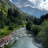 A picturesque alpine river flowing through lush Swiss mountains under a vibrant sky.
