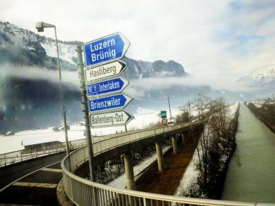 Road signs in snowy Swiss landscape with foggy mountains in the background. Captured near Sachseln, Switzerland.